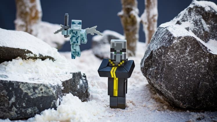 A photo of an evoker figure standing together with a vex between two stones.